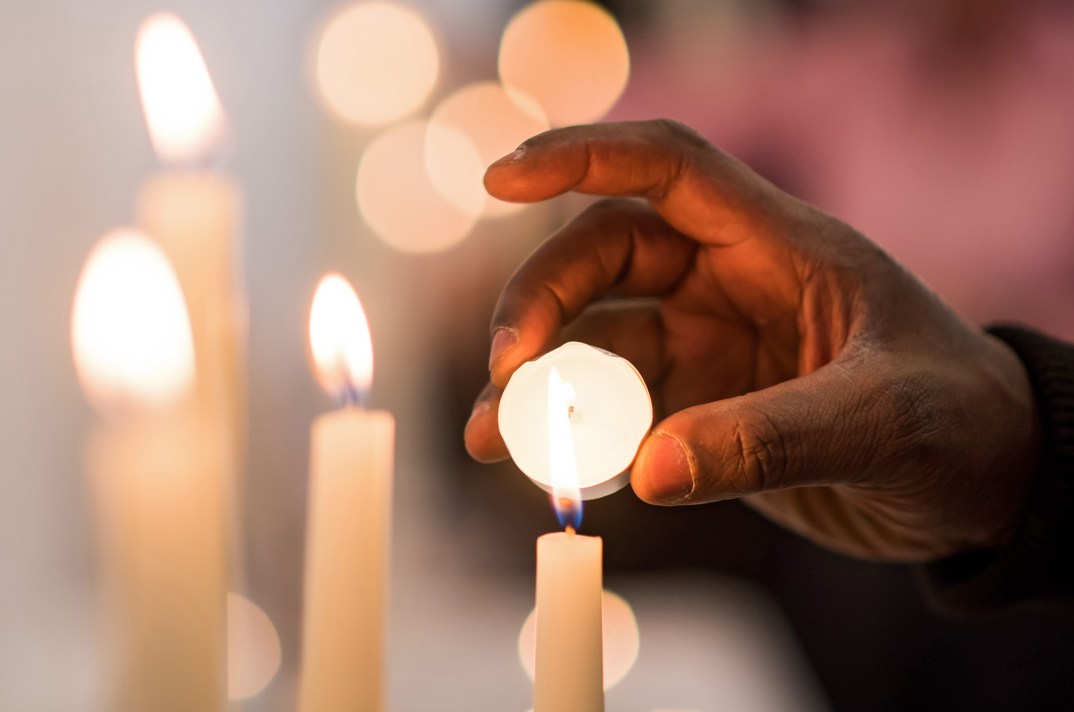 Eine Hand zündet eine Kerze an